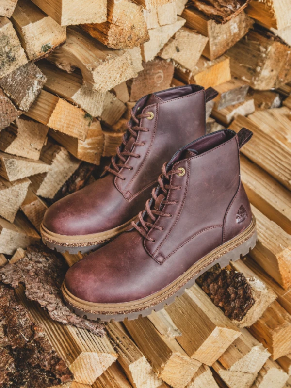 Men's brown leather lace-up boots displayed on stacked firewood