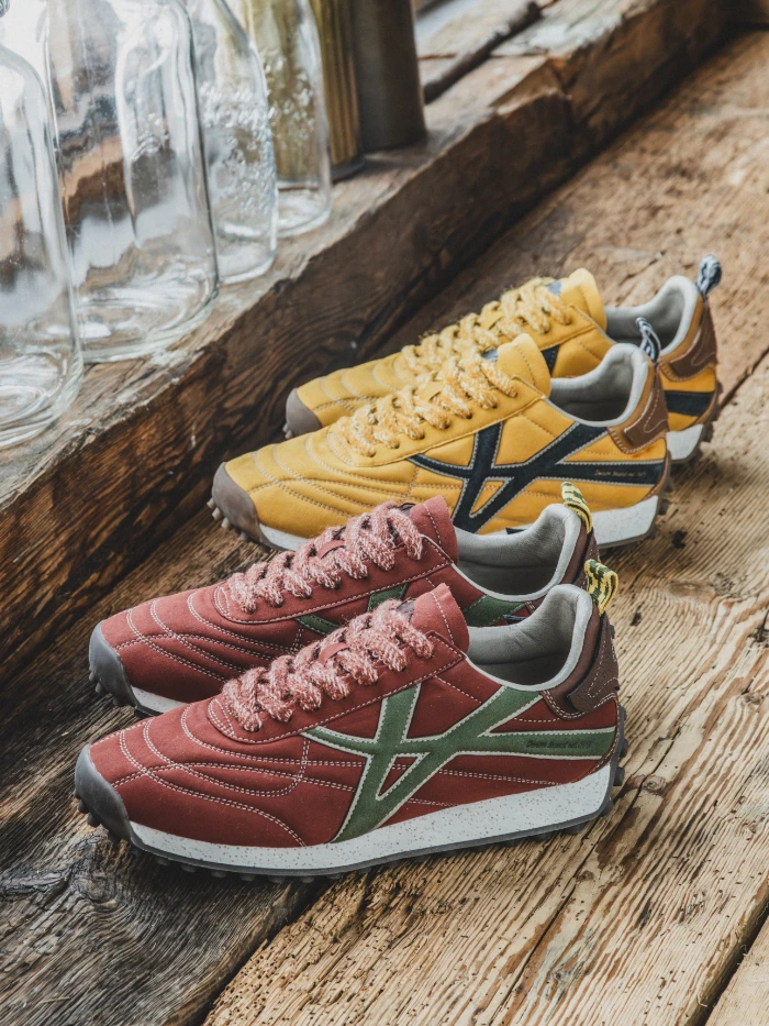 Men's casual suede sneakers in red, green, and yellow with terry laces on a wooden surface