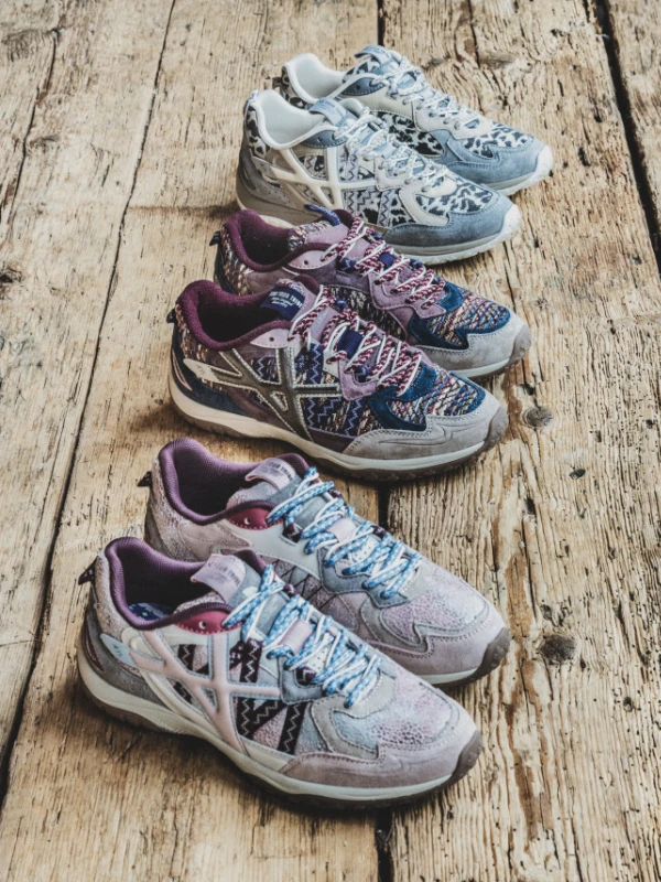 Selection of women's sneakers with ethnic patterns and leopard print arranged on a wooden floor